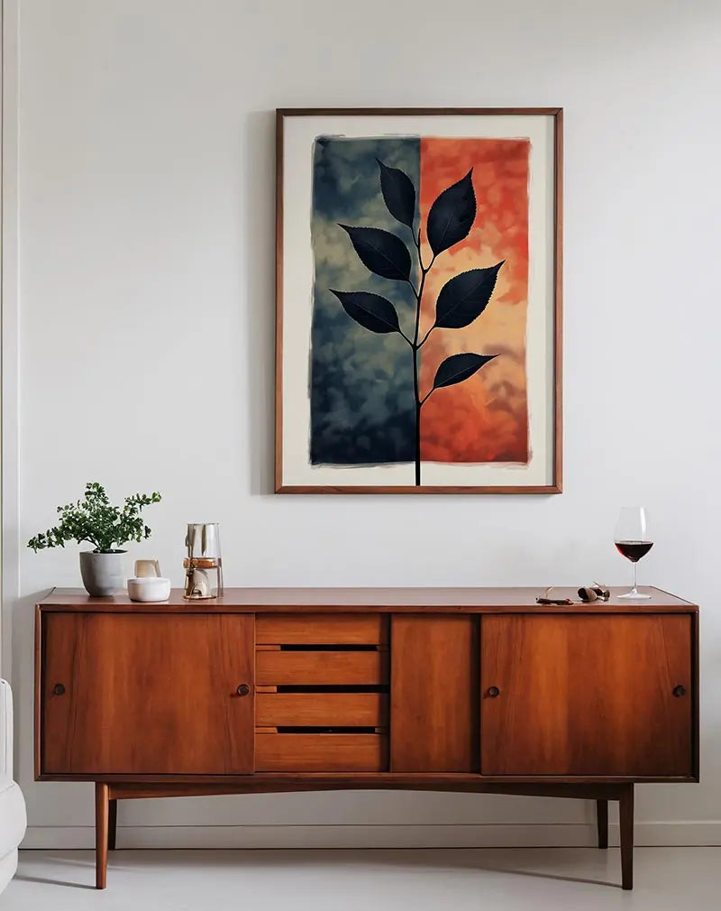 A striking illustration of a black leaf silhouette set against contrasting backgrounds of dark blue and vibrant orange. Perfect wall art for adding a bold statement to modern and minimalist spaces, bringing a touch of nature and abstract design.